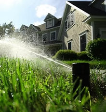 Residential sprinkler system operating in front of a newly built home