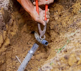 Technician repairing broken irrigation pipe underground