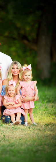 family portrait of parents in white with their quadruplet daughters in pink at home in Robinson Texas.