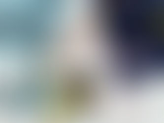 Knitting items on a white surface: floral fabric, pink yarn, needles, shears, green tube, tin, stitch markers, and a blue bag.