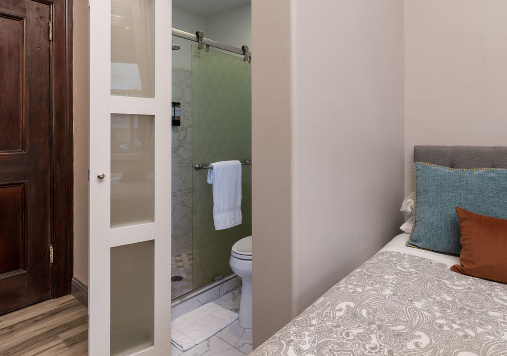 Ensuite bathroom with shower and toilet next to a bed.