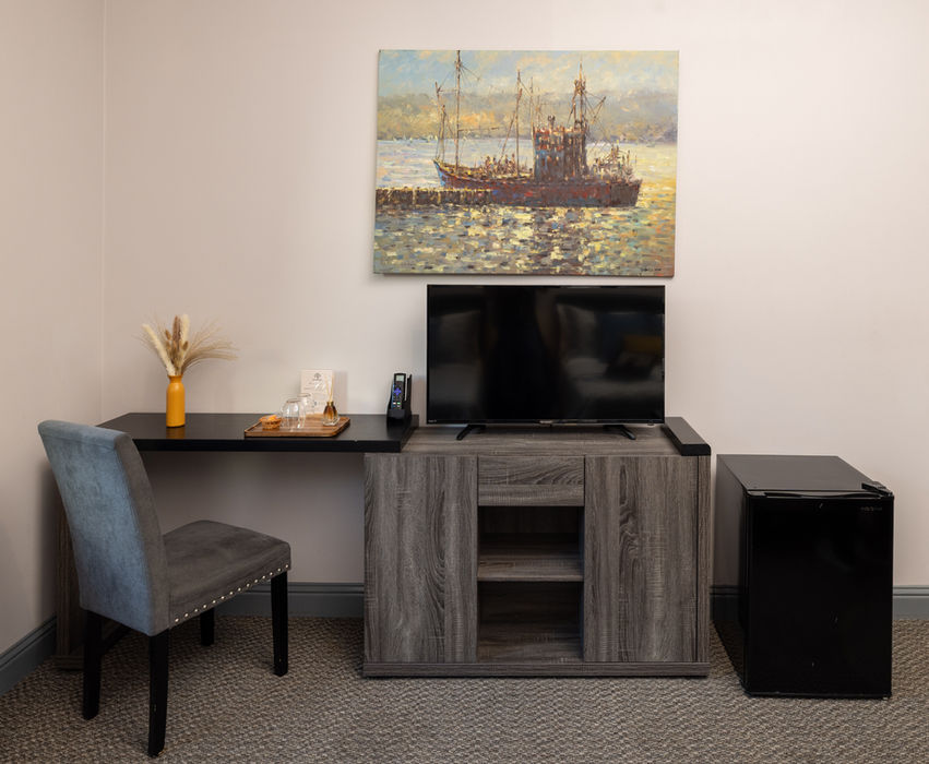 Guest room with work desk, TV, and ship painting