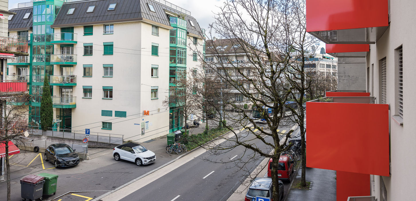 Street view, buildings, cars, and trees. Swiss Flat Rental is available.