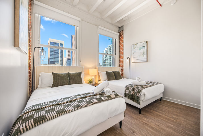 Two beds in a furnished apartment san diego with city view and windows.