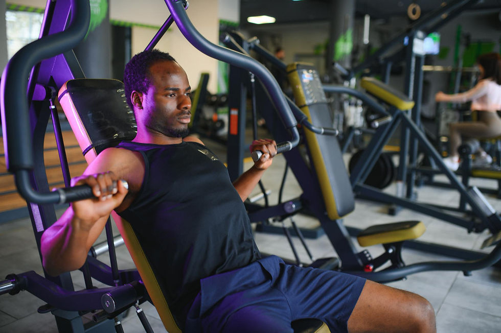 Man working out using chest press machine in a modern gym setting.