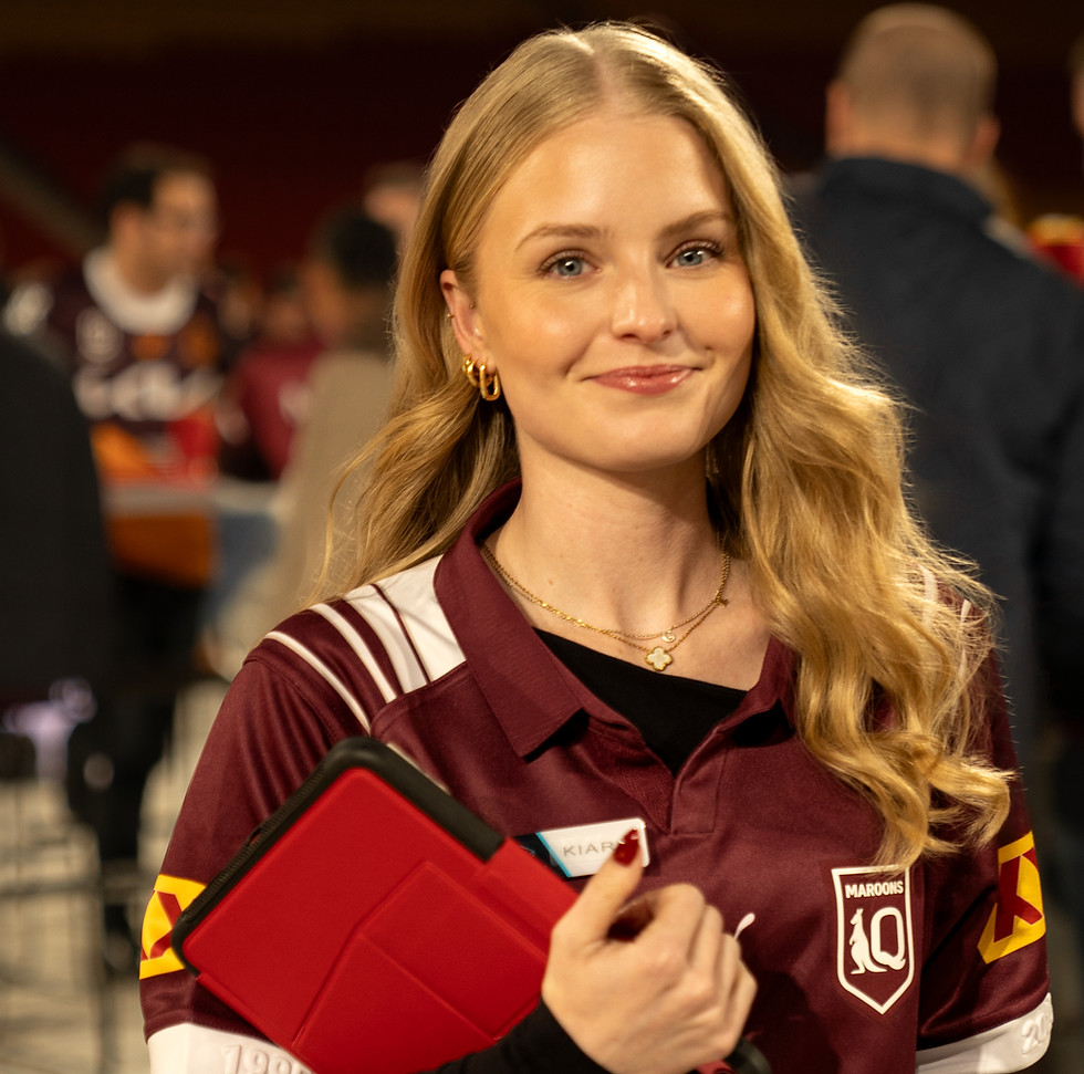 Young woman wearing maroon jersey, holding a red tablet, smiling at camera.