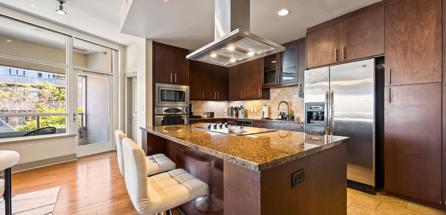 Modern kitchen with island, stainless steel appliances, and wooden cabinets. furnished rentals