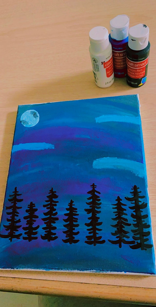 A blue moon looks over pine trees on this canvas. 