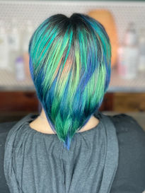 Short layered hair colored bright green and blue with a touch of pink