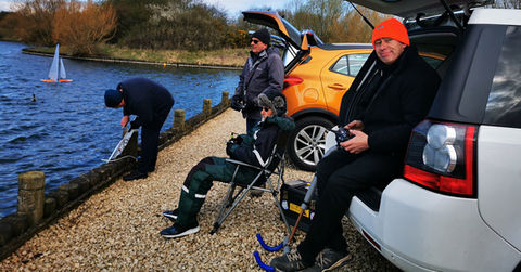 Men enjoying model sailboat racing at lake