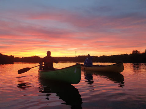 Two kayakers paddle at sunset