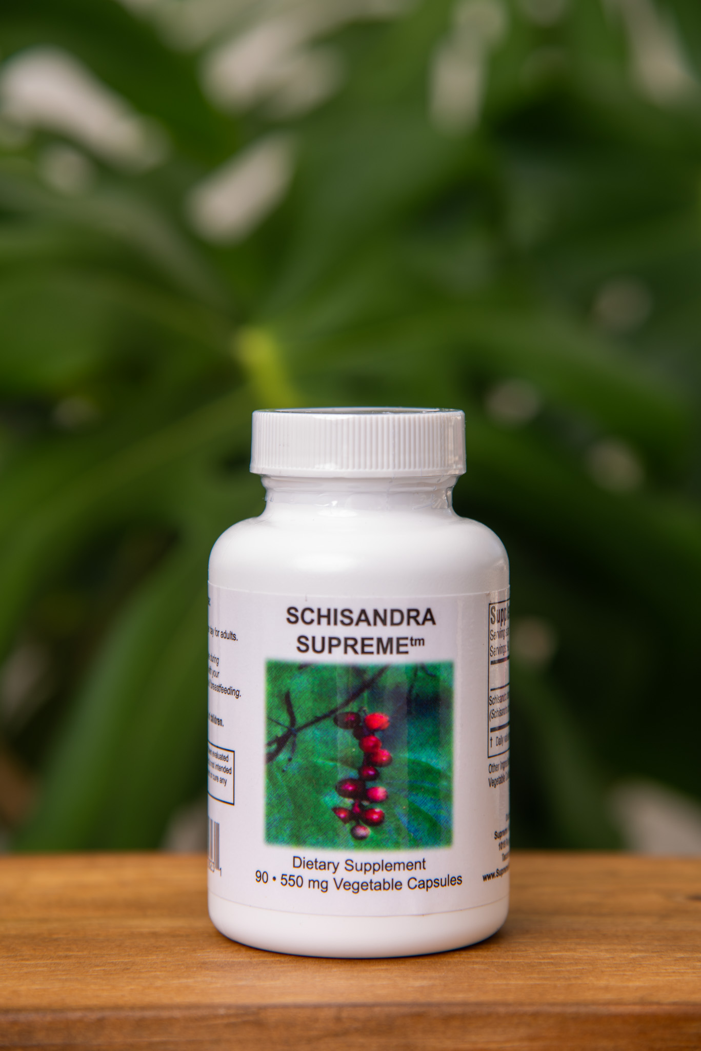 Schisandra Supreme bottle on a wooden surface against green foliage