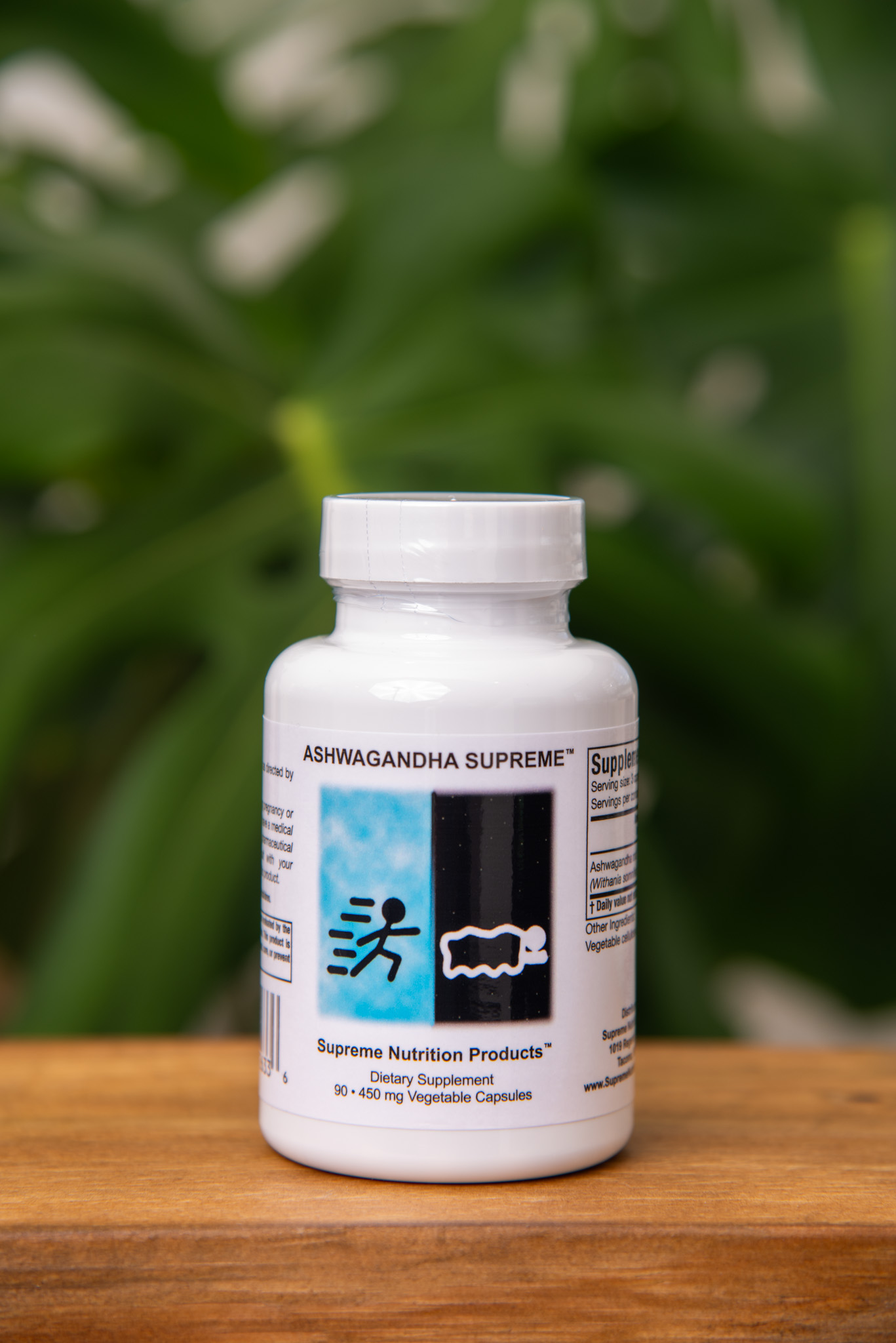 Ashwagandha Supreme bottle on a wooden surface against green foliage