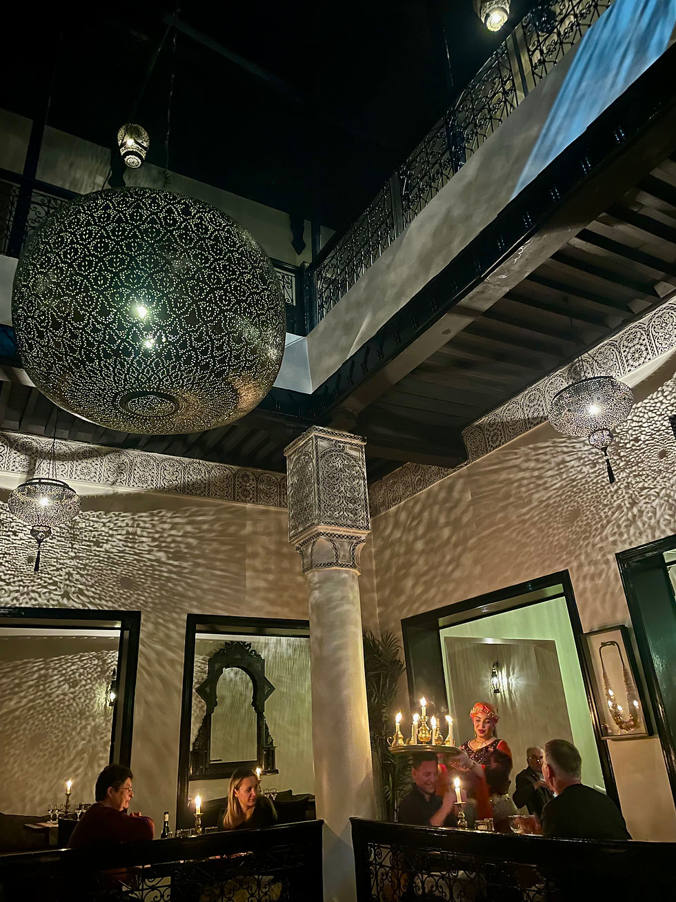 The interior of a Moroccan restaurant showing a woman balancing a tray of candles on a man's head