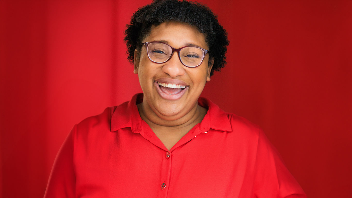 Commercial headshot of actress on bright red backdrop, happy and smiling
