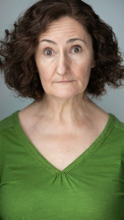 An actress wearing a green top, she has a calm expression with a diffused soft light used