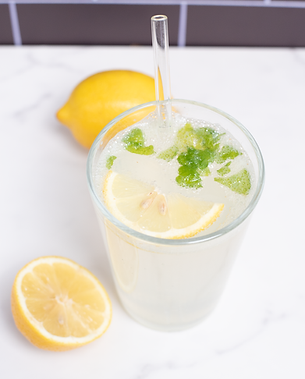 Glass of refreshing lemon detox drink with mint leaves, served with fresh lemon slices on a marble background