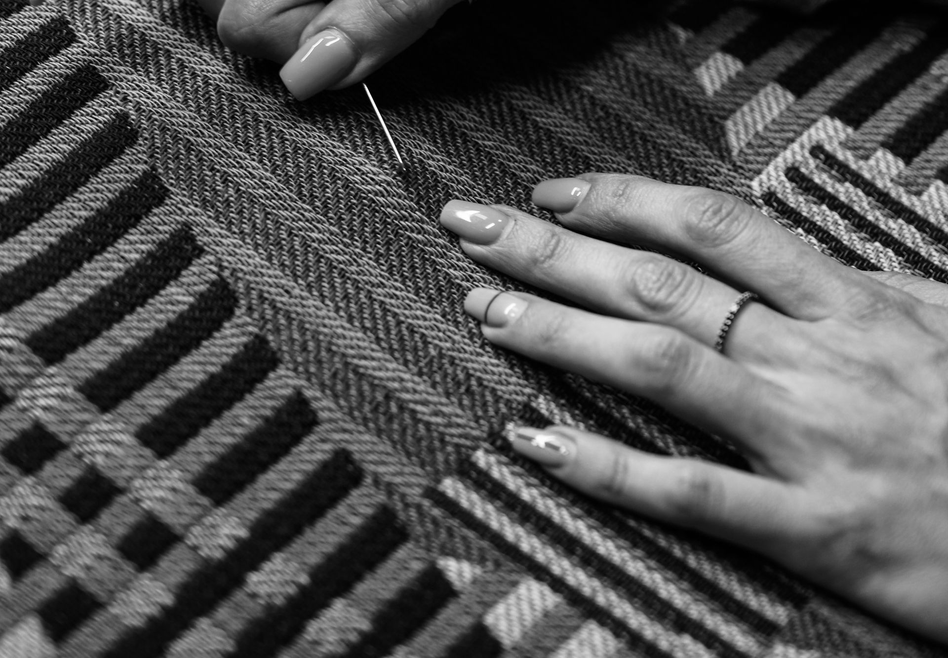 two hands mending / darning on a striped piece of fabric