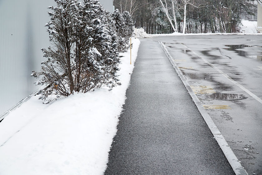 Sidewalk of industrial parking lot freshly shoveled and salted from snow and ice.