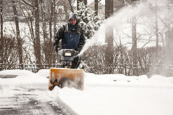 A worker operating a snow blower in the winter