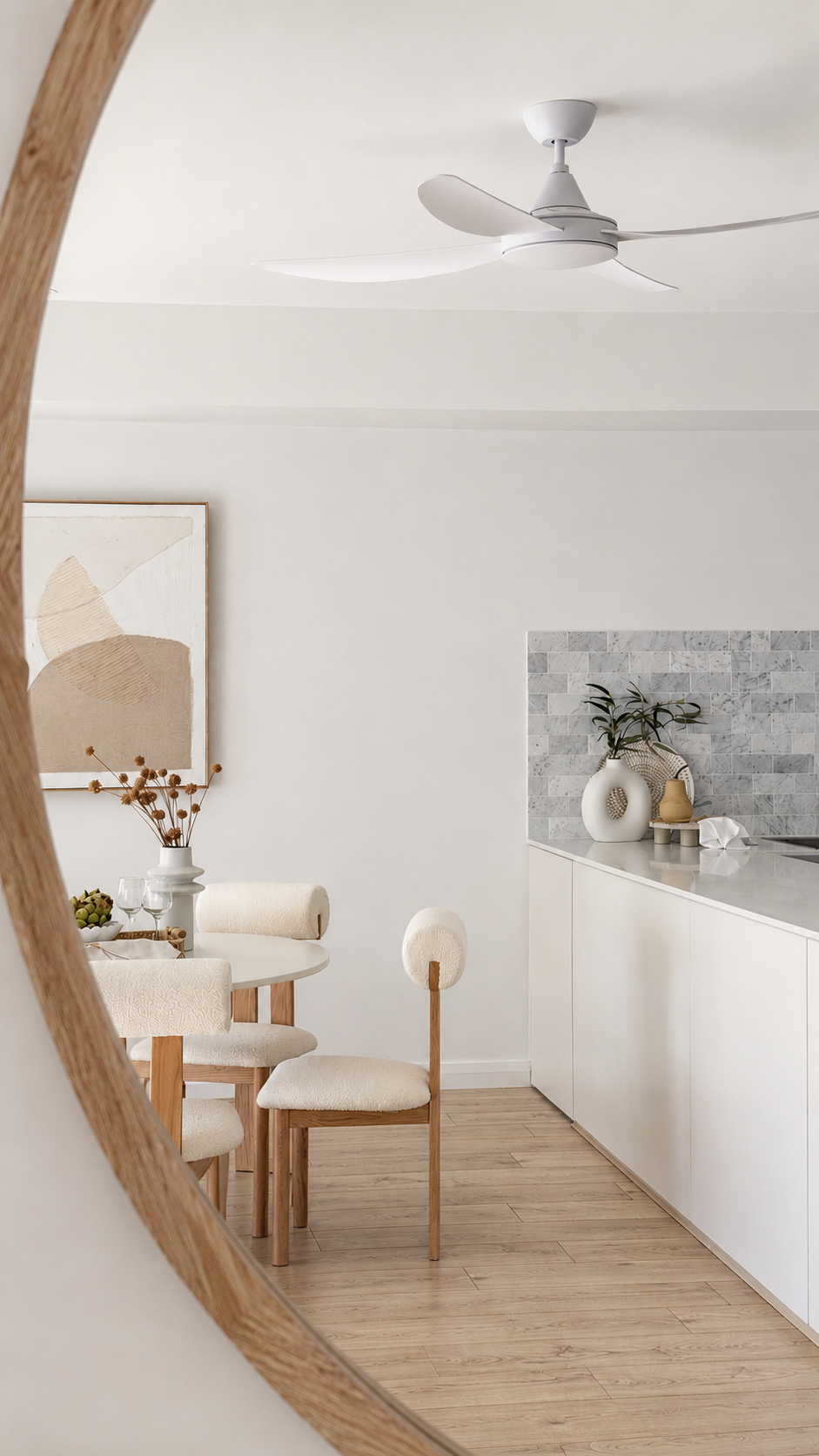 Open-plan dining room styling in a New Lambton townhouse featuring a round white table, timber dining chairs, neutral artwork and warm timber flooring.