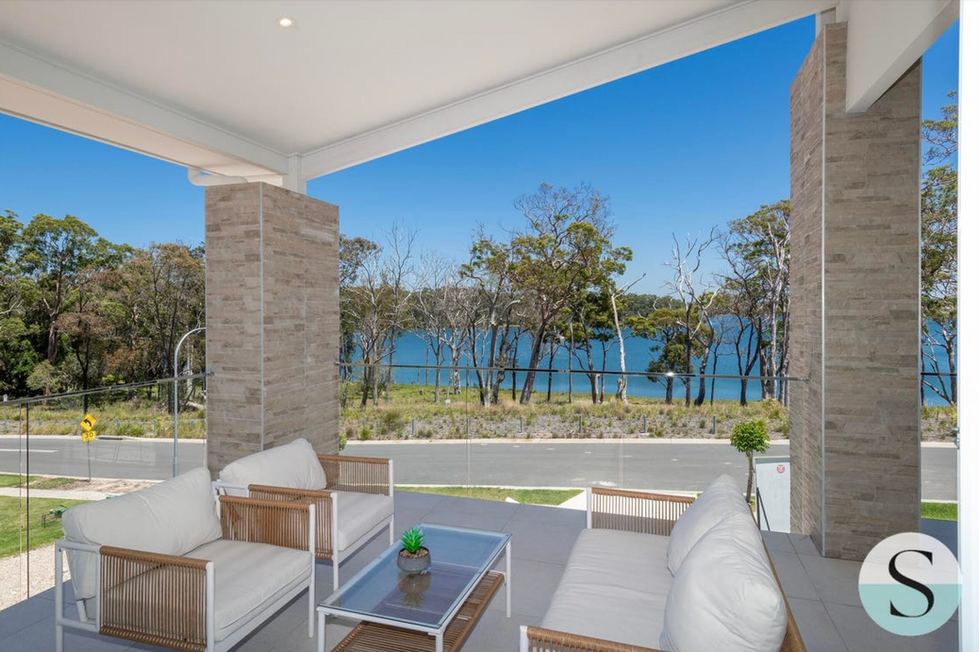 Covered outdoor entertaining balcony with waterfront outlook and modern lounge seating