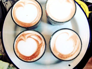 Four cappuccinos on a white enamel dinner plate with a blue trim