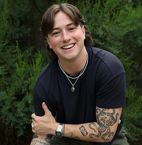 Therapist smiling warmly outdoors with lush green foliage in the background