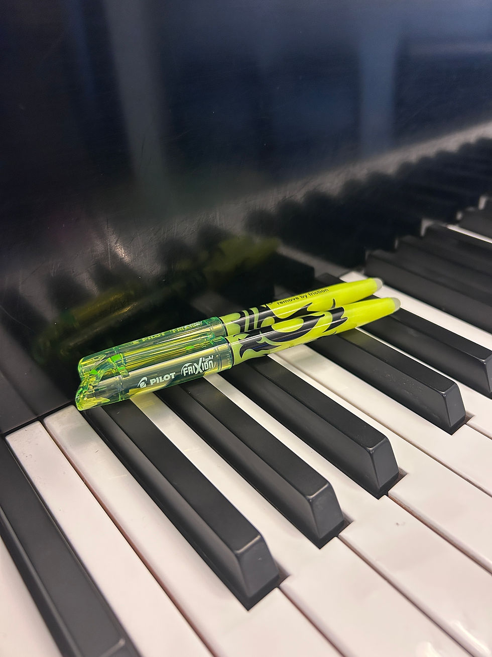 2 yellow highlighters sitting on top of piano keys