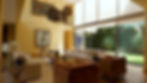 Sala de estar de una residencia en Lomas de Chapultepec, con techo de doble altura, paredes en color arena, grandes ventanales con vista a un jardín privado, muebles modernos, sillones de piel, y obras de arte en las paredes.