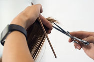 Professional hairstylist using scissors to create a precision haircut for a client in a modern salon environment.