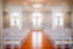 Empty wedding ceremony hall with white chairs and arched doors Weddings