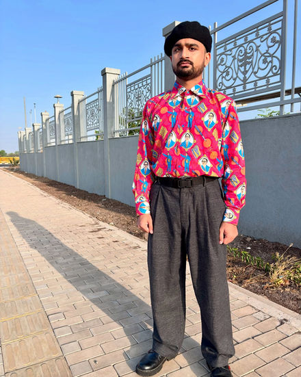 a man wearing a hat and a pink shirt stands on a sidewalk