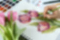 Woman painting tulips in sketchbook at white table, closeup.jpg
