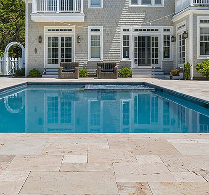 Roman travertine pool surround in a residential outdoor environment