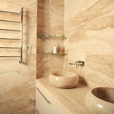 Roman travertine bathroom surfaces with integrated countertop and stone washbasins