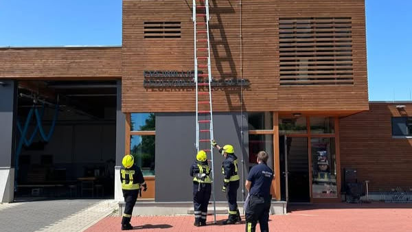 Feuerwehrleute mit Leiter vor Gebäude