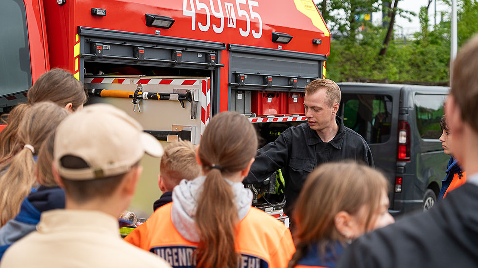 Mensch vor Gruppe und Feuerwehrauto