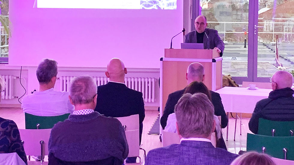 Mann hinterm Rednerpult mit Zuhörenden