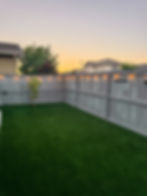 Artificial grass lushly covers a backyard, providing a low-maintenance green space