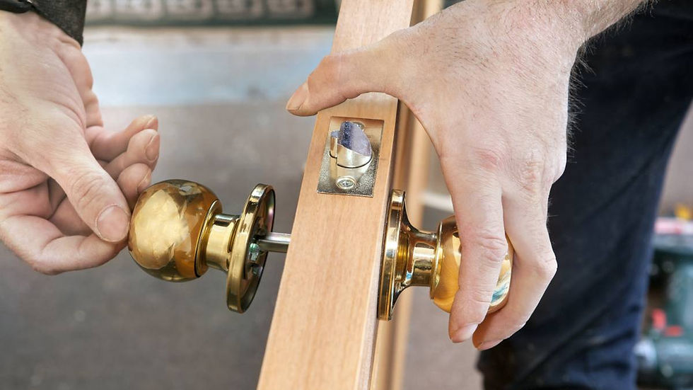 Handyman installing a brass doorknob on a wooden door.