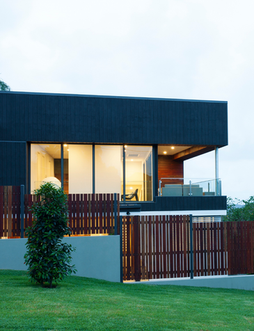 A modern minimalist house with large glass windows and a wooden fence, showcasing clean architectural lines and a contemporary design