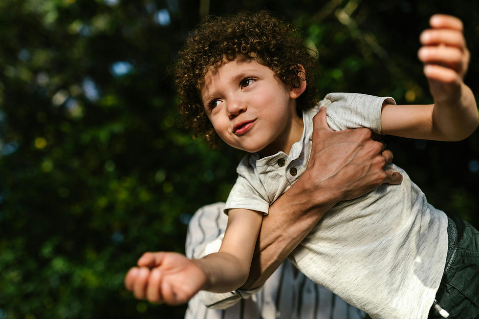Young boy with curly hair held by adult