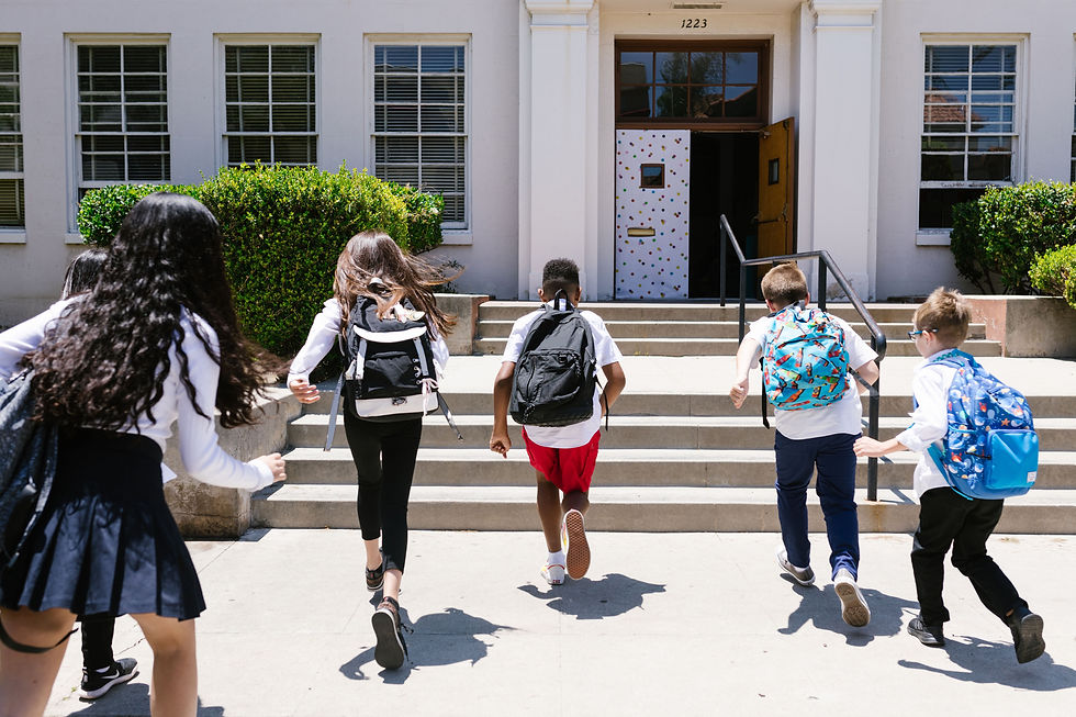 Children with backpacks hurry up steps to a school building marked 1223, sunny day, colorful door, eager mood