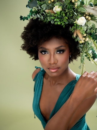 Woman in a teal dress wears a headdress of florals and greenery
