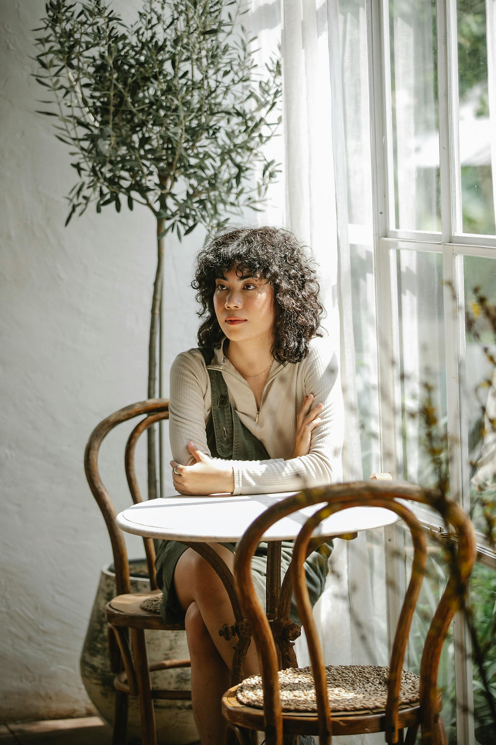 Woman with curly hair sits at cafe table