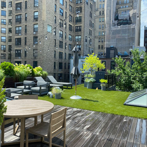 Rooftop deck with seating, green turf, and city buildings
