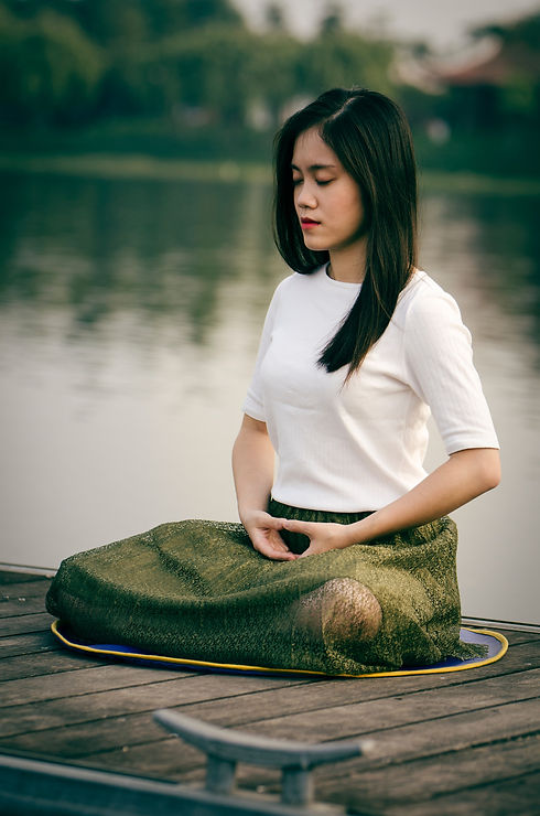 Photo of woman in seated pose with legs crossed near water