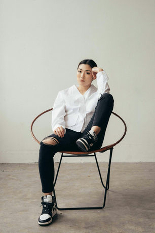 Woman sitting thoughtfully in a chair, symbolizing contemplation and introspection related to imposter syndrome and anxiety