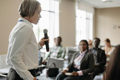 Woman speaking into a microphone to an audience